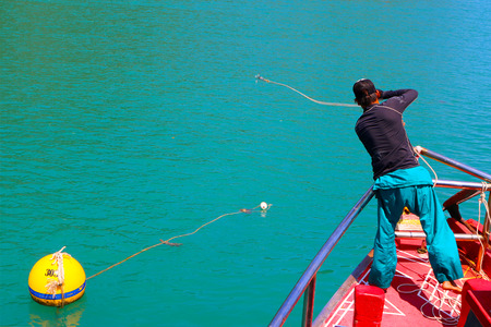 Crew are using a rope tied into a small boat with a big boat in Thailandの写真素材