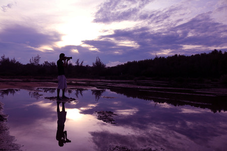 Mirror of purple sky in the morning reflection to the water with shadow of photographer in Thailand.の写真素材