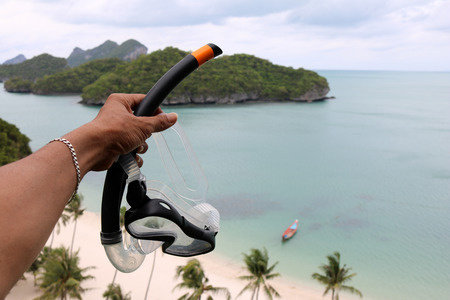 Hand holding the diving mask on the view point of ang thong archipelago island. Thailand.の写真素材