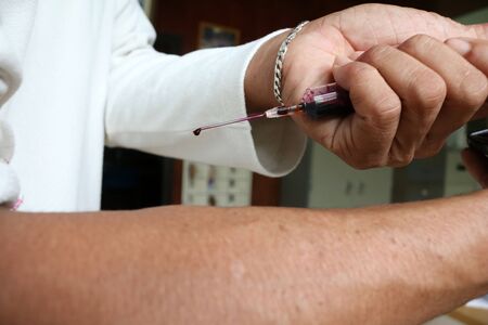 Men using a injection needles , and blood in the syringe.