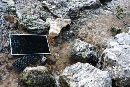 The computer under the surface of the water in a waterfall,Screen with keyboard and mouse.の写真素材