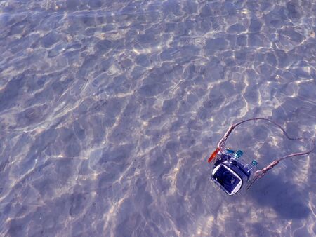 Compact camera and housing floating on the sea with reflections surface.の写真素材