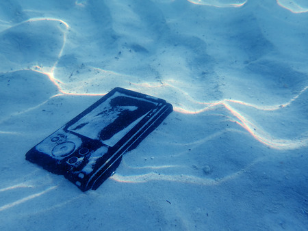 Compact camera on the sand with light reflected under the sea water.の写真素材