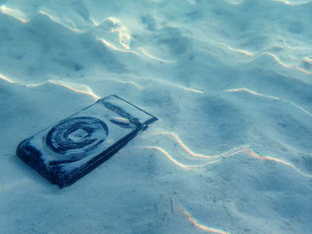 Compact camera on the sand with light reflected under the sea water.の写真素材