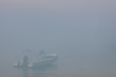 Blurred dinghies boat in the fog-covered sea.
