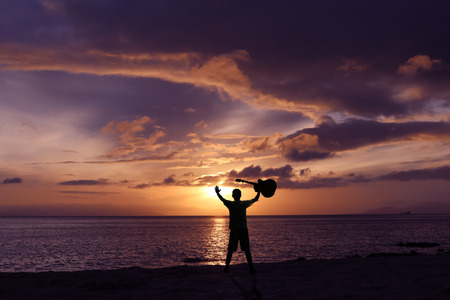 Men throwing the guitar with a red sky sunrise background.の写真素材