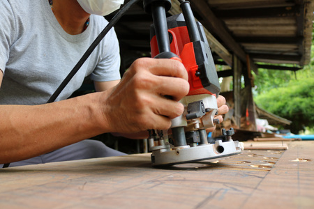 Asian workers using electric routering to cut down stripes on the wood.の写真素材