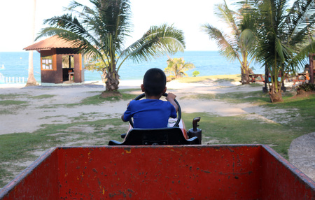 Asian boy learned to drive a truck on the beach.の写真素材