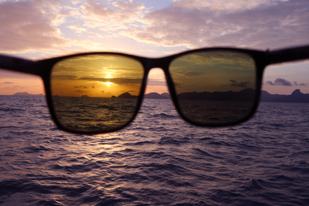 Sunglasses with a sunset in the sea.の写真素材