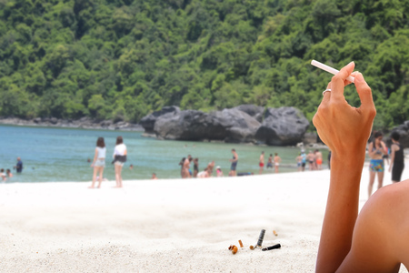 Smoking with cigarette butts ashtray on the sand on the beach and travel activityの写真素材