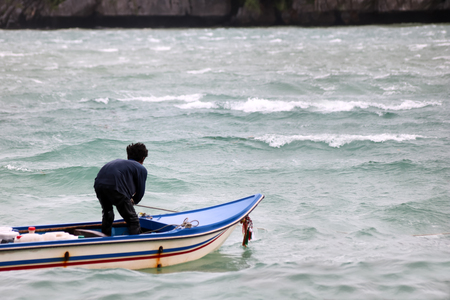 Local asian fishermen with small boats at the seaside in stormy weather.
