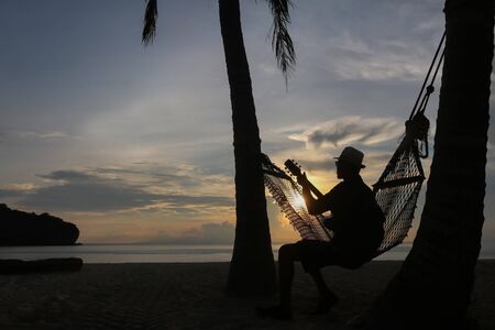 Guitarist on the beach with the sunrise in Thailand.の写真素材