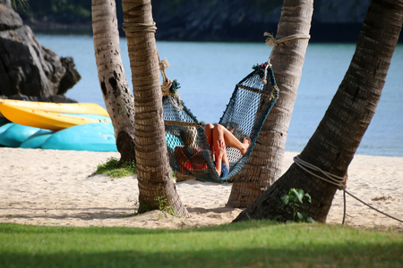 Tourists girls relaxing and lying on a hammock on the beach,Samui island Thailand.の写真素材