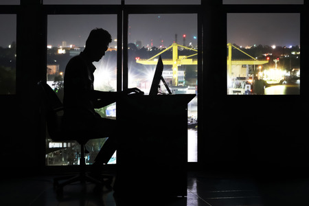 Silhouette asian business man working on a computer in the office at night.の写真素材