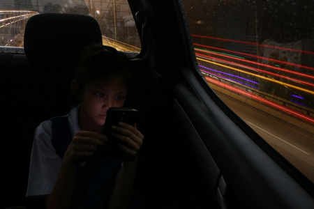 Asian students girl enjoy a phone on the personal cars while back home during the evening.