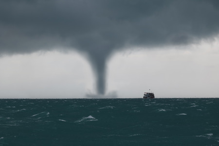 Tornado and storm cloud in the sea while the ship is sailing in the ocean.の写真素材