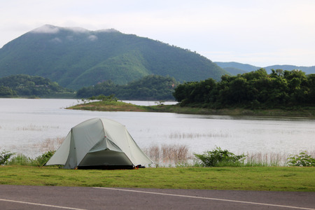 Campsite and tents on the lawn with beautiful green nature landscapes of dam water, forests, and mountains in Thailand.の写真素材