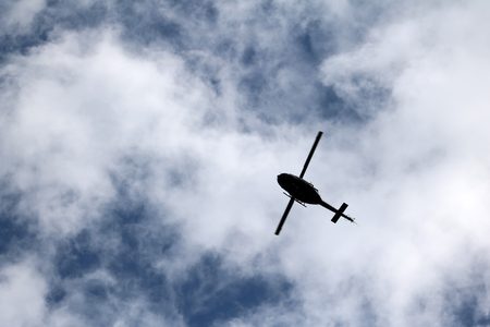 A flying black helicopter aircraft during the flight with blue sky
