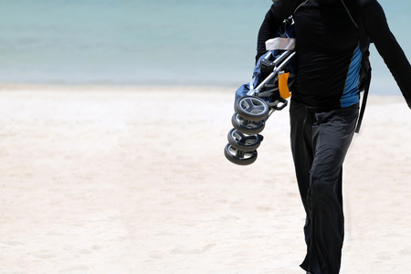 Tourists man are walking, holding a baby strollers and luggage on the white sand  beach, Parenting and travel concept.の写真素材
