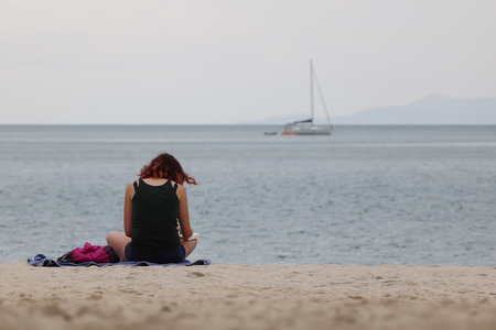 Tourist girl reading a book relaxing on a tropical beach in the evening.Thailandの写真素材
