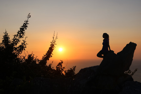 Happy woman enjoying on the top of the mountain at sunset. Silhouette sky background.の写真素材