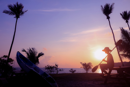 Local people hold the paddle with kayak on the beach at sunrise.Silhouette asian fisherman with purple sky background.の写真素材