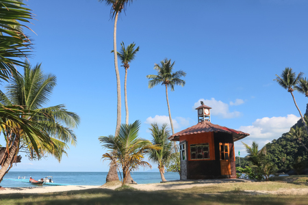 Hut or Cottage on the coconut beach. The clock tower or lifeguard tower against the blue sky and ocean background.の写真素材