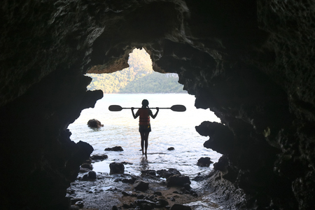 Kayaking in the cave, Asian girls holding the paddle stands in front of a cave by the sea in Thailandの写真素材