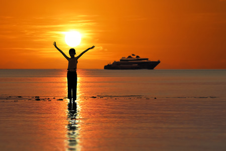 Silhouette of single Asian girl enjoying herself during sunset on the beach red sky background.の写真素材