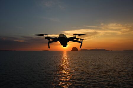 Drones while flying in the sky at sunset, Ocean and island backgrounds in Thailandの写真素材