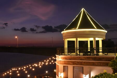A view pavilion beside the Mekong River with lights and night sky and beautiful mountains in Laos.の写真素材