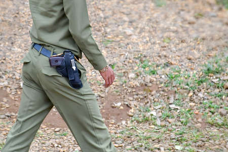 A gun tucked at the waist of a police officer in a uniform in Laos, Asia.