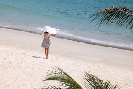 A woman in comfortable clothes walks on the beach in Thailandの写真素材