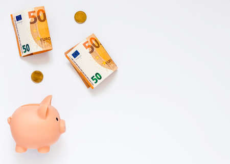 A piggy bank, paper money worth 50 euros and coins of 20 cents on a white background. The concept of...
