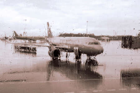 Unfocused view of the plane through the airport window, with raindropsの写真素材