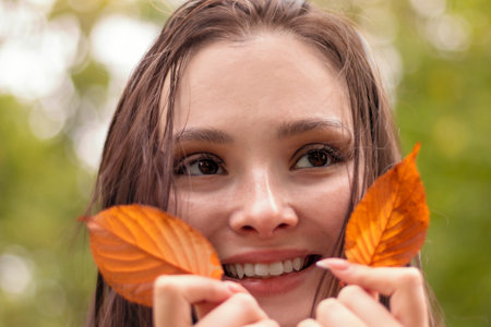 Portrait of a young woman, she smiles and enjoys a warm autumn dayの写真素材