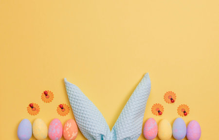 Colorful Easter eggs and rabbit ears made of napkins. Easter background with free spaceの写真素材