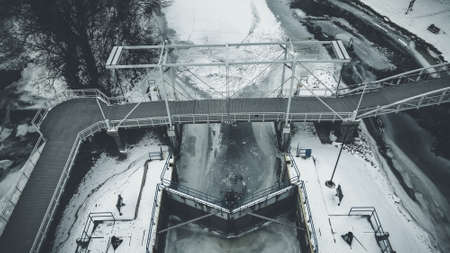 A winter landscape of the frozen canal at a public park. The doors frozen shut have only a sliver of blue color on the railing.の写真素材