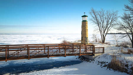 The lake is frozen over with a blue sky but this old landmark still stands watch over the water.の写真素材