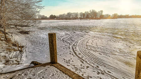The ice fishermen drive out to the lake on snowmobiles or walk on the ice. The sun is slowly setting over the frozen landscape.の写真素材