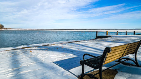 Frozen landscape from bench perspective over icy lakefront viewの写真素材