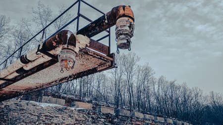 A very rusty old pipe extends over this quarry in winterの写真素材