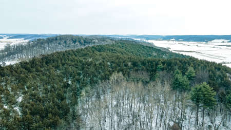 Snow covers the hills and fields with farm fields between the slopes.