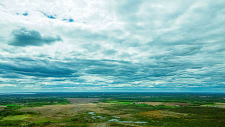 A cloudy sky extends to the horizon over a rural grassy view of Wisconsin USA in springtime