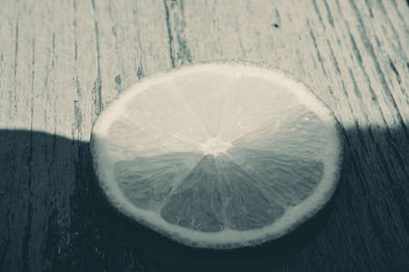 BW View of Sun lights up half the cut lime sitting on a wooden tableの写真素材