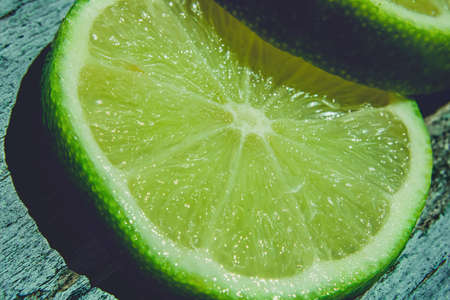 Sitting out on the bright sun a pair of sliced limes on a blue wooden deckの写真素材