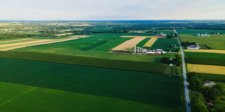 A view of rural wisconsin landscape with farms and fields. Trees surround the area with a blue sky...