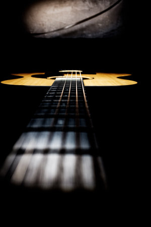 Acoustic guitar in a dark room. Selective focus. Toned.