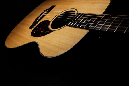 Acoustic guitar on a black background, close-up, selective focus