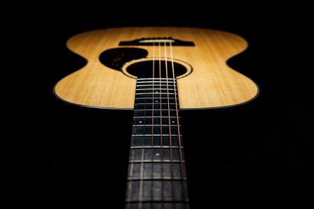 Acoustic guitar on a black background, close-up, selective focus